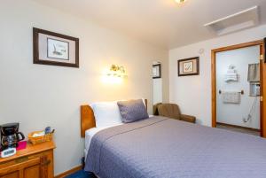 a bedroom with a blue bed and a mirror at Cascade Motel in Oakridge +8 photos