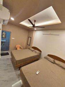 Cette chambre comprend deux lits et un ventilateur de plafond. dans l'établissement Snekam Inn, à Tiruvannāmalai