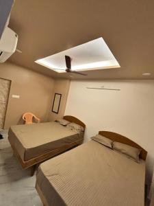 une chambre avec deux lits et un ventilateur de plafond dans l'établissement Snekam Inn, à Tiruvannāmalai