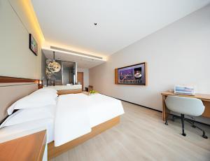 a bedroom with a white bed and a desk at Leaf Hotel in Yantaiqian