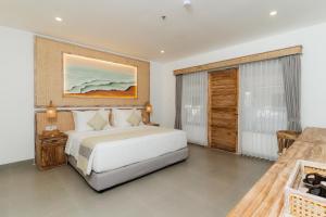 a bedroom with a large white bed and a table at Vila Ombak in Gili Trawangan