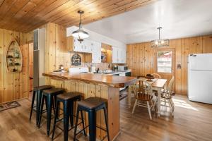 una cocina con paredes de madera y una gran isla con taburetes. en Tranquil Retreat with Fenced Backyard, Hot tub & Bar, en Big Bear City