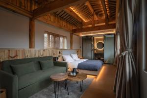 een slaapkamer met een bed, een bank en een tafel bij Humble abode of happiness - Mountain View Wabi-sabi Lodge in Lijiang