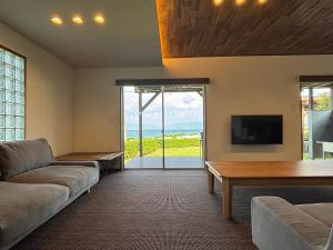 a living room with a couch and a flat screen tv at Seaside Villa KAMANO in Aji