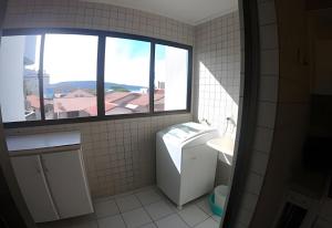 La salle de bains est pourvue d'un lave-linge, d'un lavabo et d'une fenêtre. dans l'établissement Apartamento com VISTA para o MAR no centro de Bombinhas, à Bombinhas 9 autres photos