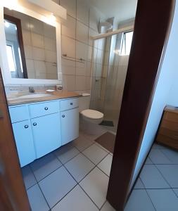 une salle de bain avec toilettes, lavabo et miroir dans l'établissement Apartamento com VISTA para o MAR no centro de Bombinhas, à Bombinhas