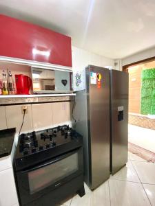 eine Küche mit einem Herd und einem Kühlschrank aus Edelstahl in der Unterkunft Casa Aconchegante no Coração de Arraial - Com Churrasqueira Privativa in Arraial do Cabo + 14 Fotos