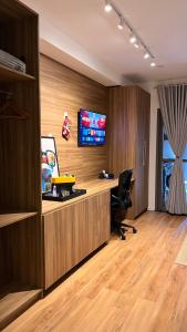 an office with a desk and a tv on a wall at Apartamento Giardino Maia, Café da Manhã cortesia em dias úteis in Guarulhos