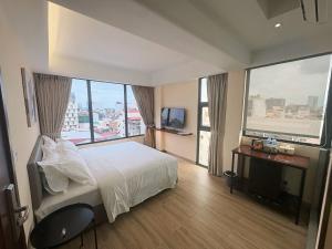 a bedroom with a white bed and large windows at The Guesthouse By SH in Phnom Penh