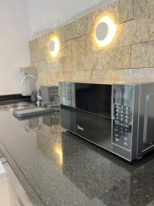 un micro-ondes posé sur un comptoir dans une cuisine dans l'établissement Giardino, Studio Moderno Aconchegante e Tranquilo, à Guarulhos 14 autres photos