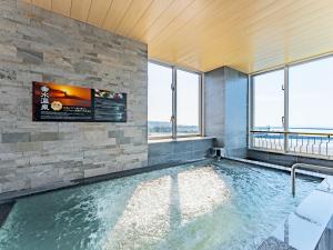 a swimming pool in a building with windows at LiVEMAX RESORT Sakurajima Sea Front in Tarumizu