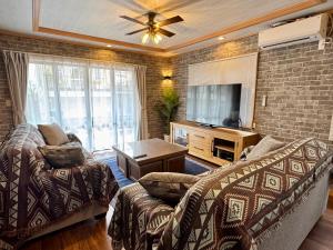 een woonkamer met een bank en een tv bij ヴィラ マイラニハウス沖縄 in Hamakawa