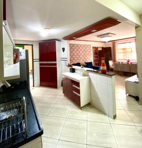 eine Küche mit einem roten Kühlschrank und weißen Schränken in der Unterkunft Casa Aconchegante no Coração de Arraial - Com Churrasqueira Privativa in Arraial do Cabo