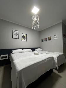 een slaapkamer met een groot wit bed met een kroonluchter bij Casa aconchegante em local Estratégico in Foz do Iguaçu