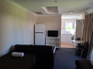 a living room with a couch and a table with a refrigerator at City Park Motel and Apartments in Wagga Wagga