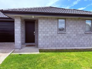 une maison avec une porte noire et une pelouse verte dans l'établissement Stunning Modern Retreat, à Hastings