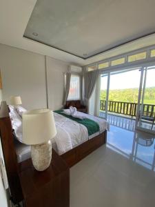 a bedroom with a bed with a lamp and a balcony at Gunung Homestay Bali in Tabanan +40 photos