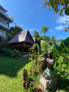 a statue of a woman sitting on a rock in a garden at Gunung Homestay Bali in Tabanan
