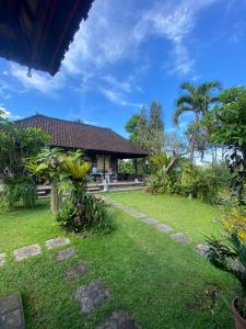 a house with a yard with grass and trees at Gunung Homestay Bali in Tabanan