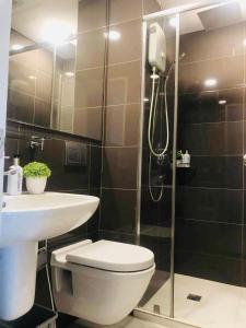 a bathroom with a shower and a toilet and a sink at Acqua Private Residences Livingstone Tower in Sampong