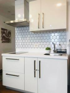 a white kitchen with white cabinets and a sink at Acqua Private Residences Livingstone Tower in Sampong