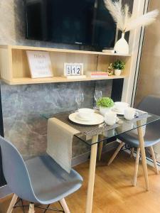 a dining room table with two chairs and a television at Acqua Private Residences Livingstone Tower in Sampong +10 photos