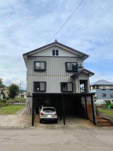 a car parked in front of a house with a garage at Snowshine House - Family Friendly in Joetsu