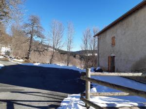 a fence in the snow next to a building at Gîte chaleureux en Auvergne avec animaux admis, idéal pour nature et randonnées - FR-1-496-197 in La Chambonie
