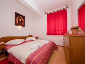 a bedroom with a bed and red curtains at Apartments Scerbe Gordana & Miljenko Rab - Two Bedroom Apartment with Terrace 1 in Otok Rab