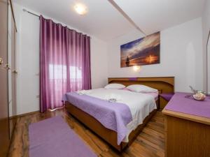 a bedroom with a bed with purple sheets and a window at Apartments Scerbe Gordana & Miljenko Rab - Three Bedroom Apartment with Terrace 2 in Otok Rab
