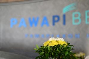 a vase with yellow and white flowers in front of a sign at Pawapi Beach Resort in Ko Muk