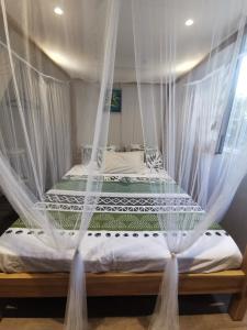 een bed met een klamboe erover in een slaapkamer bij Villa Goyave in Le Robert