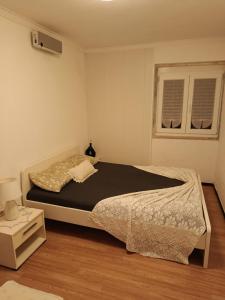a bedroom with a large bed and a window at Ginjals-67 Quarto Branco in Almargem do Bispo
