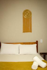 a bed with white sheets and ahat on the wall at Morada do Lago in Palmas