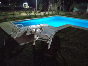 a swimming pool with two chairs and a table next to it at Cabañas Punta Iglesia 4 in Paso de la Patria +5 photos