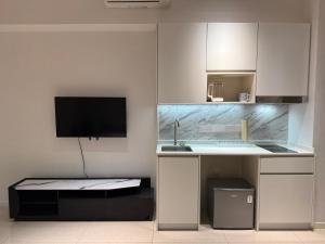 een keuken met witte kasten, een wastafel en een tv bij Bay Suite at Kota Kinabalu - 8Avenue in Kota Kinabalu
