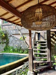 uma cesta de vime pendurada no teto ao lado de uma piscina em Bali Bohemia Huts em Ubud