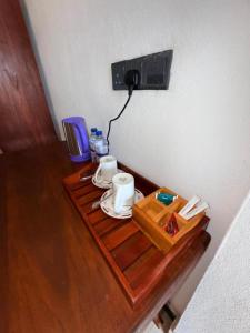 Ein Tisch mit zwei Tassen und einem Telefon an der Wand in der Unterkunft Asai surf inn Arugambay in Arugam Bay