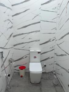 ein Bad mit einem WC und einer weißen Wand in der Unterkunft Asai surf inn Arugambay in Arugam Bay