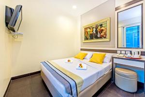 a bedroom with a bed with yellow pillows and a tv at Hotel 81 Bugis in Singapore