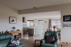 a living room with two green chairs and a kitchen at Bicheno Gardens in Bicheno