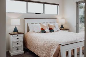 a bedroom with a white bed with pillows and two lamps at Bicheno Gardens in Bicheno