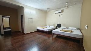 two beds in a room with wooden floors at Kamath regency and cottages in Dharmastala