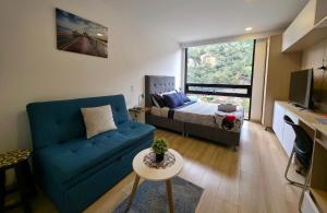ボゴタにあるAH/Loft vista natural, Coworking, Terraza, Usaquénの青いソファとベッドのあるリビングルーム