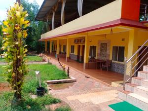 a house with a porch and a wooden deck at Kamath regency and cottages in Dharmastala