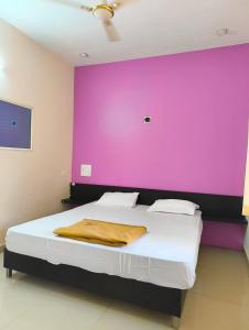 ein Schlafzimmer mit einer lila Wand und einem Bett in der Unterkunft Kamath regency and cottages in Dharmastala