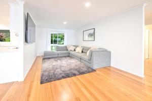 a living room with a gray couch and wooden floors at River Shack Ballina 