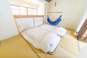 京都市にあるGuesthouse Tonton Nobuの白いシーツが敷かれた部屋にベッドが2つ