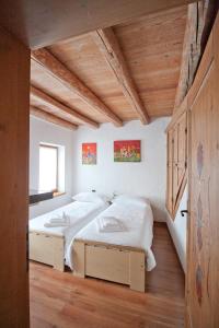 two beds in a room with white walls and wooden floors at In Cima alla Contrada in Pieve di Cadore
