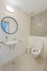 Un baño con inodoro, lavabo y espejo. en מיני פנטהאוס נווה גן Mini Penthouse by Lake Neve Gan, en Petaj Tikva